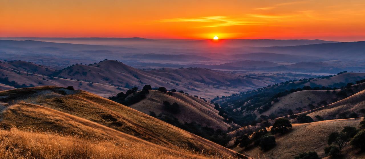 Golden San Joaquin Valley hills at dawn, layered ridgelines under an orange sunrise.